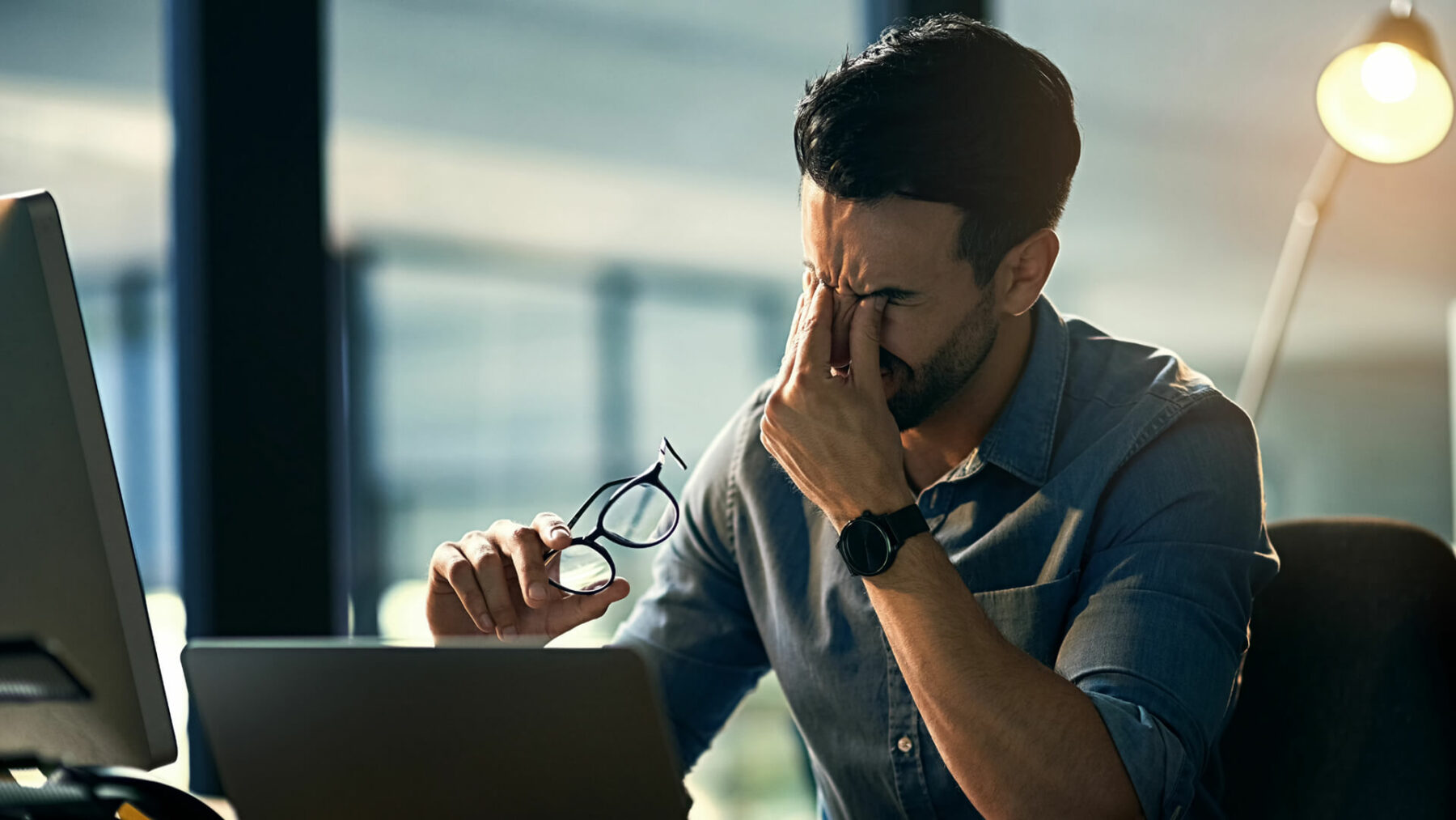 a stressed person holding their face in front of a computer