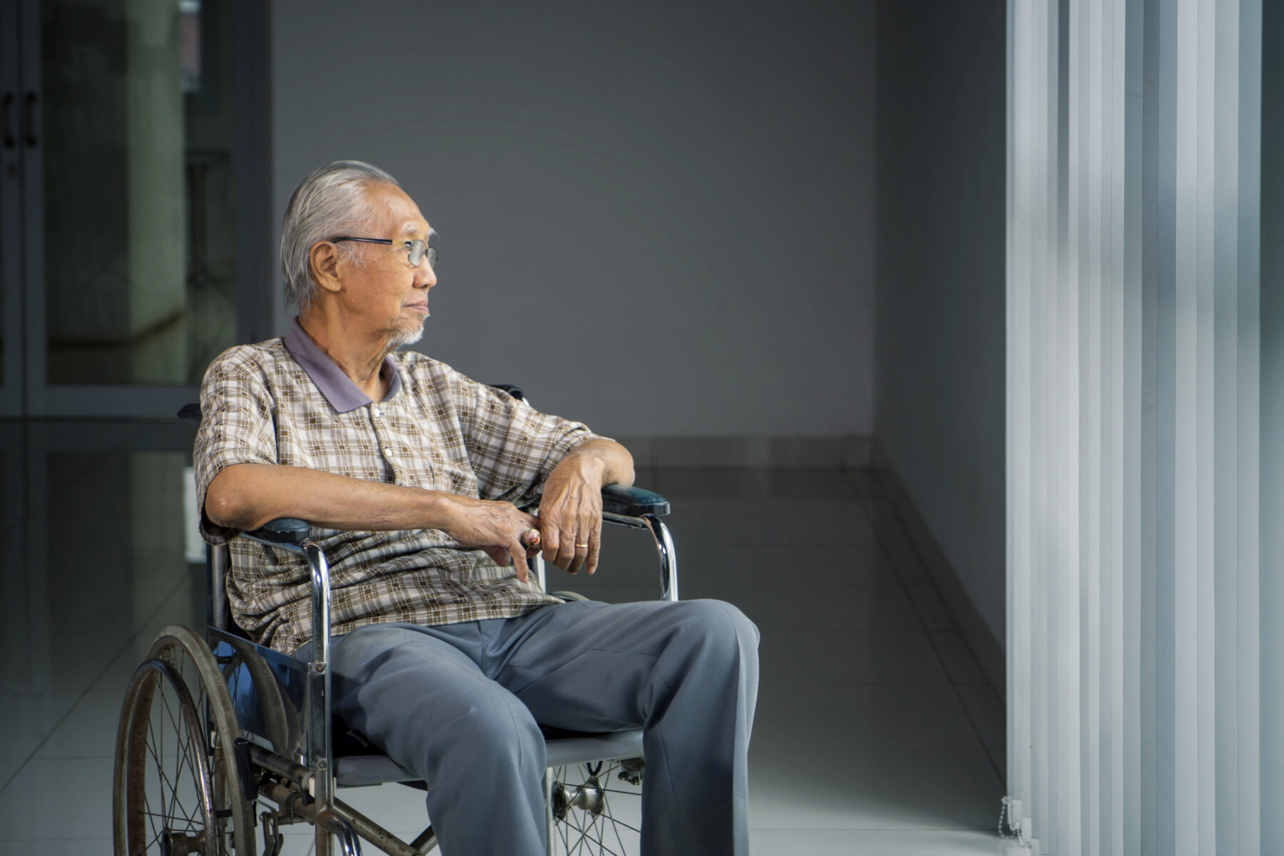 Elderly Man in a wheelchair looking out the window